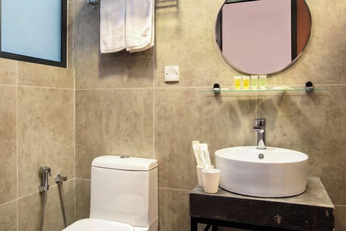 A bathroom with a toilet, sink, and mirror.