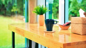 Una mesa de madera con una planta en maceta, una taza azul y una cesta tejida.