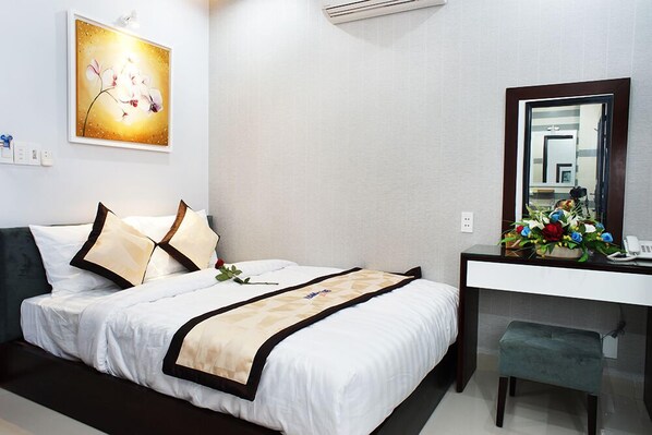 Habitación de hotel con cama, escritorio, espejo y aire acondicionado instalado en la pared.