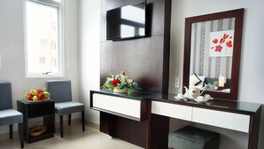 A modern room with a glass-top desk, two chairs, a television, a mirror, and a window. - Hanoi Blue Hotel - The Water Front (Da Nang)