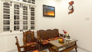 Una habitación tradicional con un conjunto de sofá, una mesa de centro de vidrio y un cuadro en la pared.