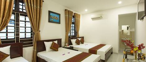 A hotel room with three beds, a desk, and a chair.