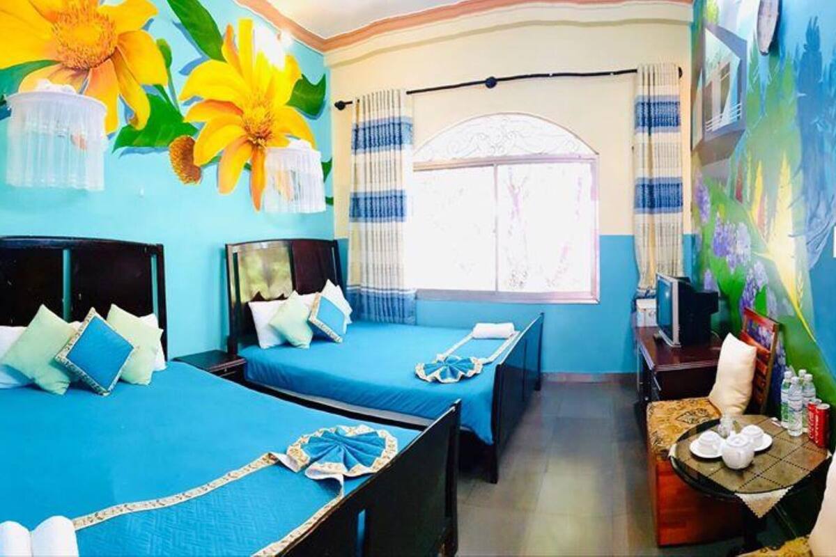A hotel room with two beds, a dining area, and a mural on the wall.