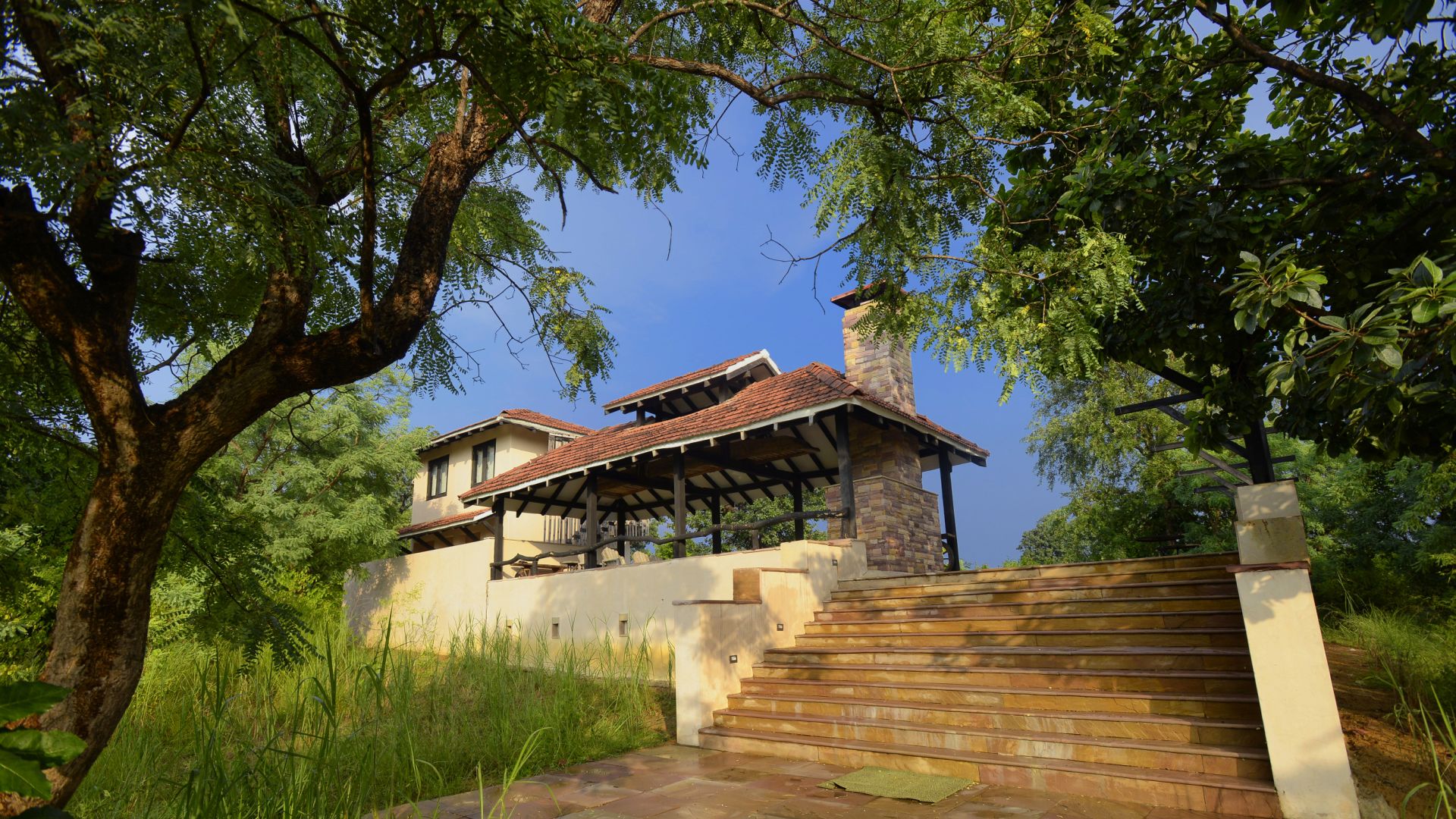 A two-story house with a covered patio and a stone staircase leading to the entrance.