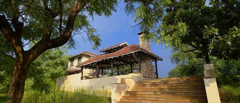 A two-story house with a covered patio and a stone staircase leading to the entrance.