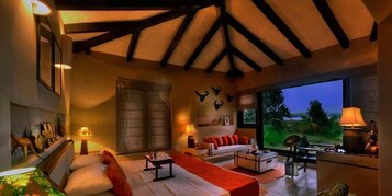 Un salón amplio con techos altos, un ventanal con vistas al exterior, chimenea y una zona de estar acogedora.
