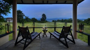 Relax in a serene outdoor setting with two comfortable chairs and a scenic view of a lush field, distant water, and mountains.