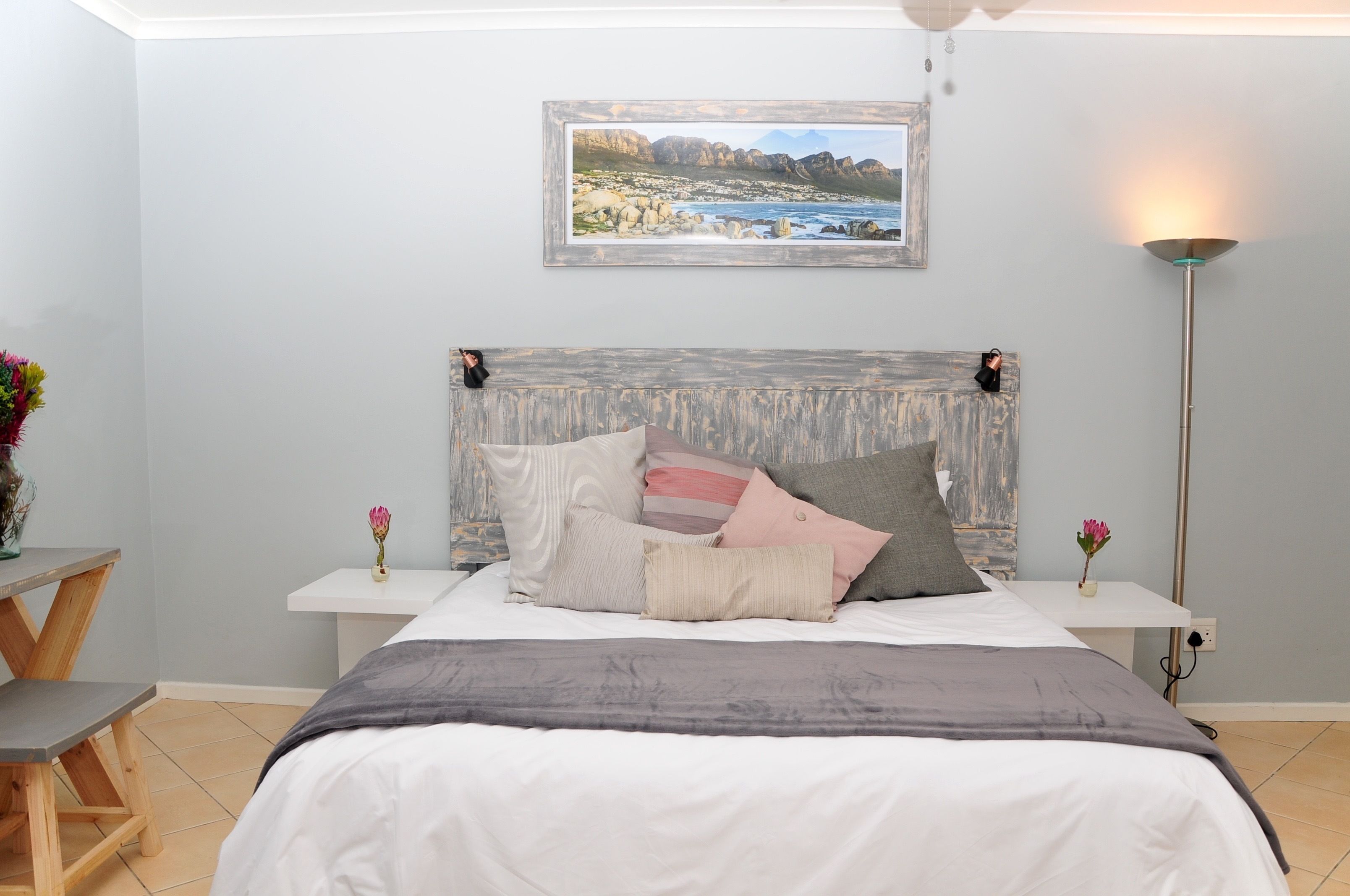 A bedroom with a bed, bedside tables, a lamp, and a framed picture on the wall.