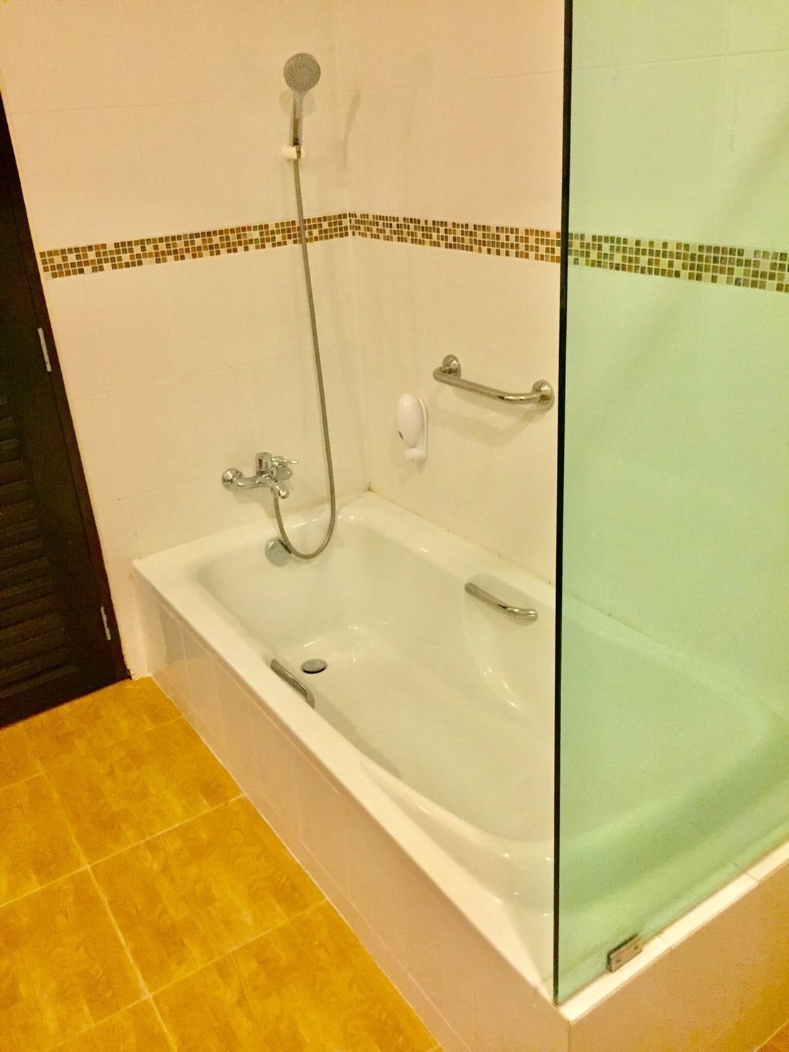 A bathroom with a bathtub, a shower, and a hand soap dispenser.