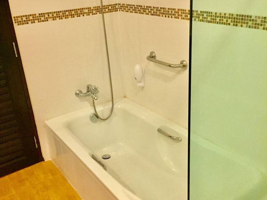 A bathroom with a bathtub, a shower, and a hand soap dispenser.