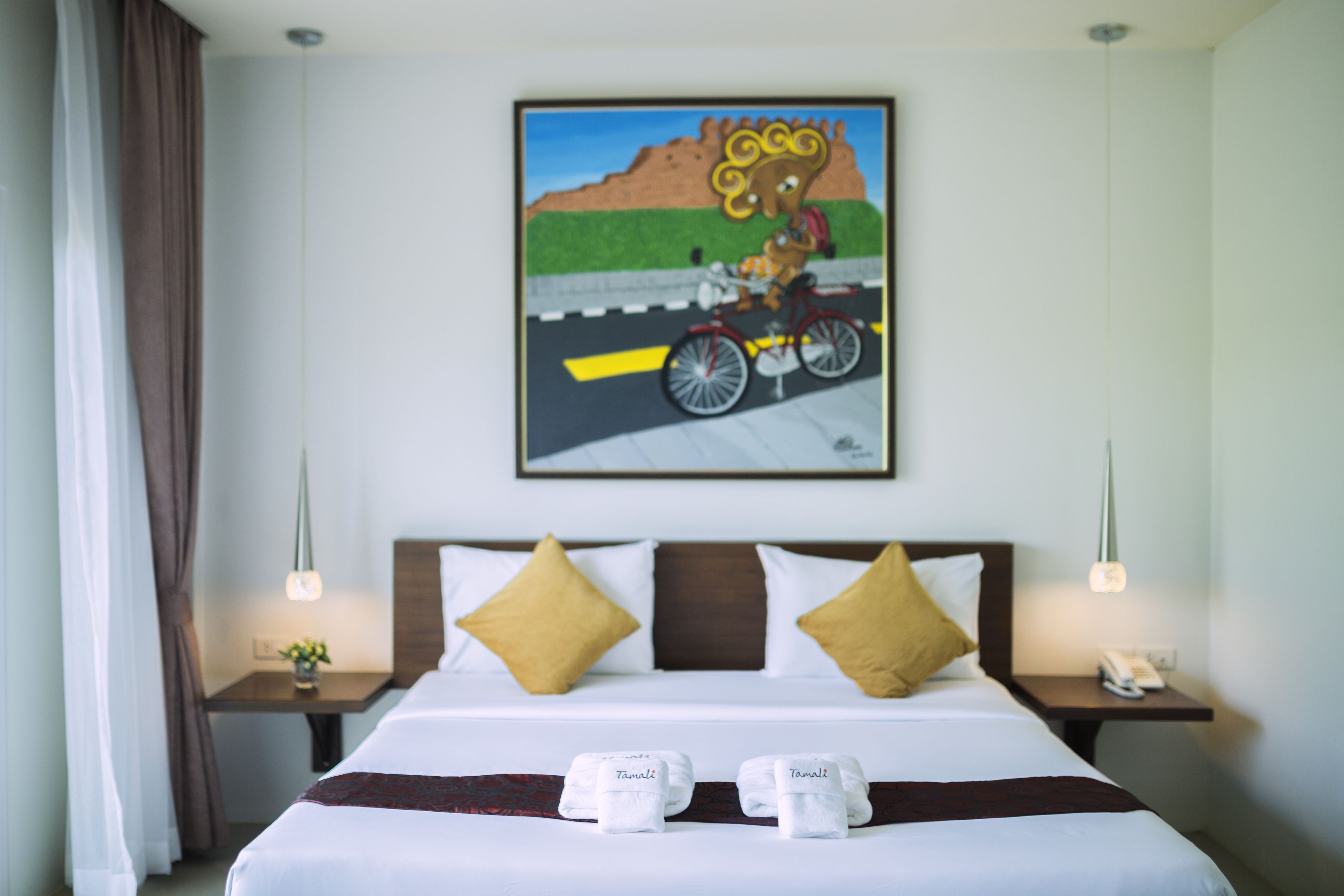 A hotel room with a bed, two nightstands, a painting, and a window with curtains.