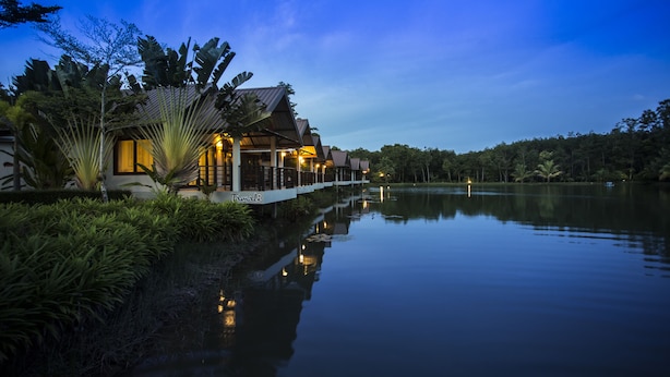 A lakeside resort with a wooden structure, a white deck, and lush greenery. - Tamali Hotel (Phra Phrom)