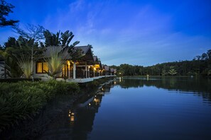 A lakeside resort with a wooden structure, a white deck, and lush greenery. - Tamali Hotel (Phra Phrom)