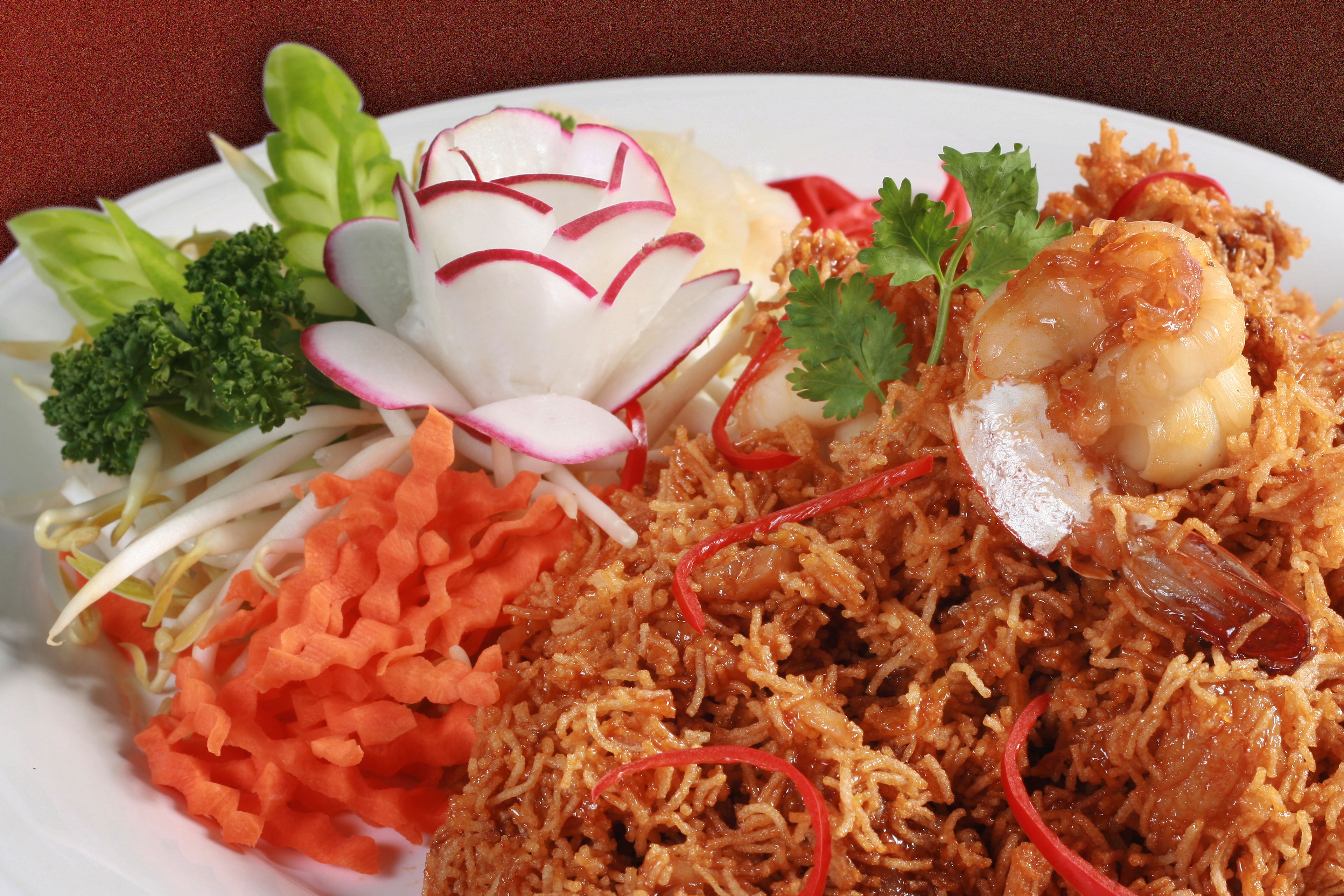 A plate of food with shredded meat, vegetables, and a shrimp garnish.