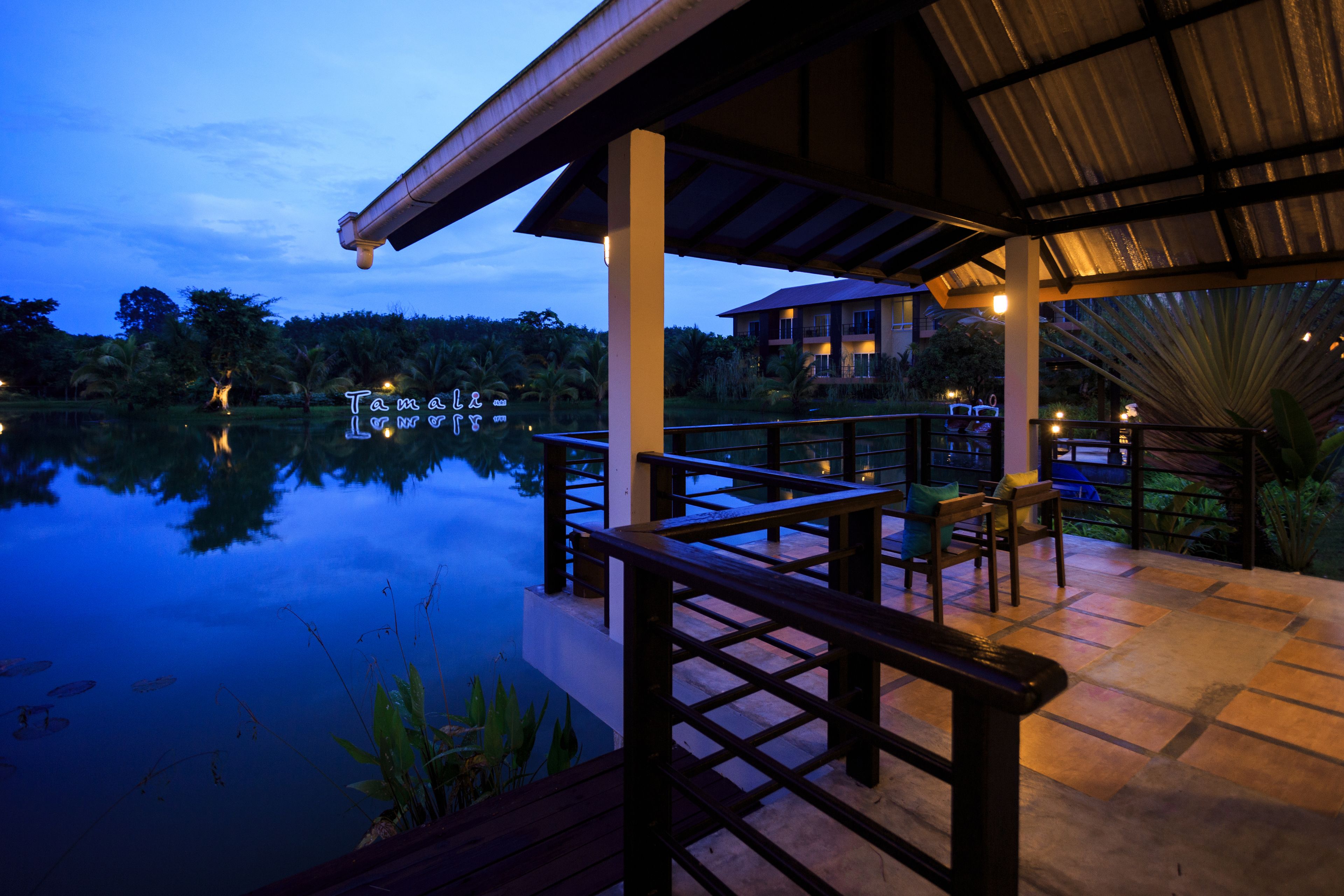 A waterfront hotel with a covered deck, a pool, and a view of the surrounding landscape.
