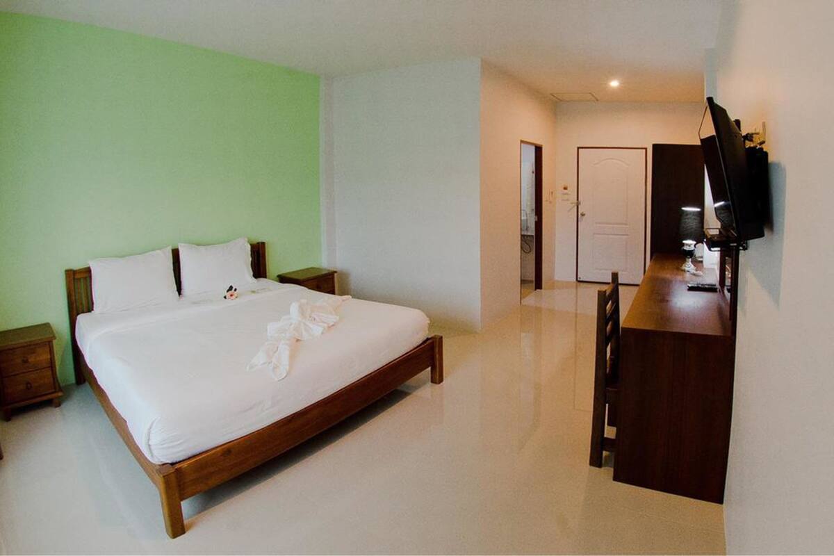 A hotel room with a wooden bed, a desk, and a television.