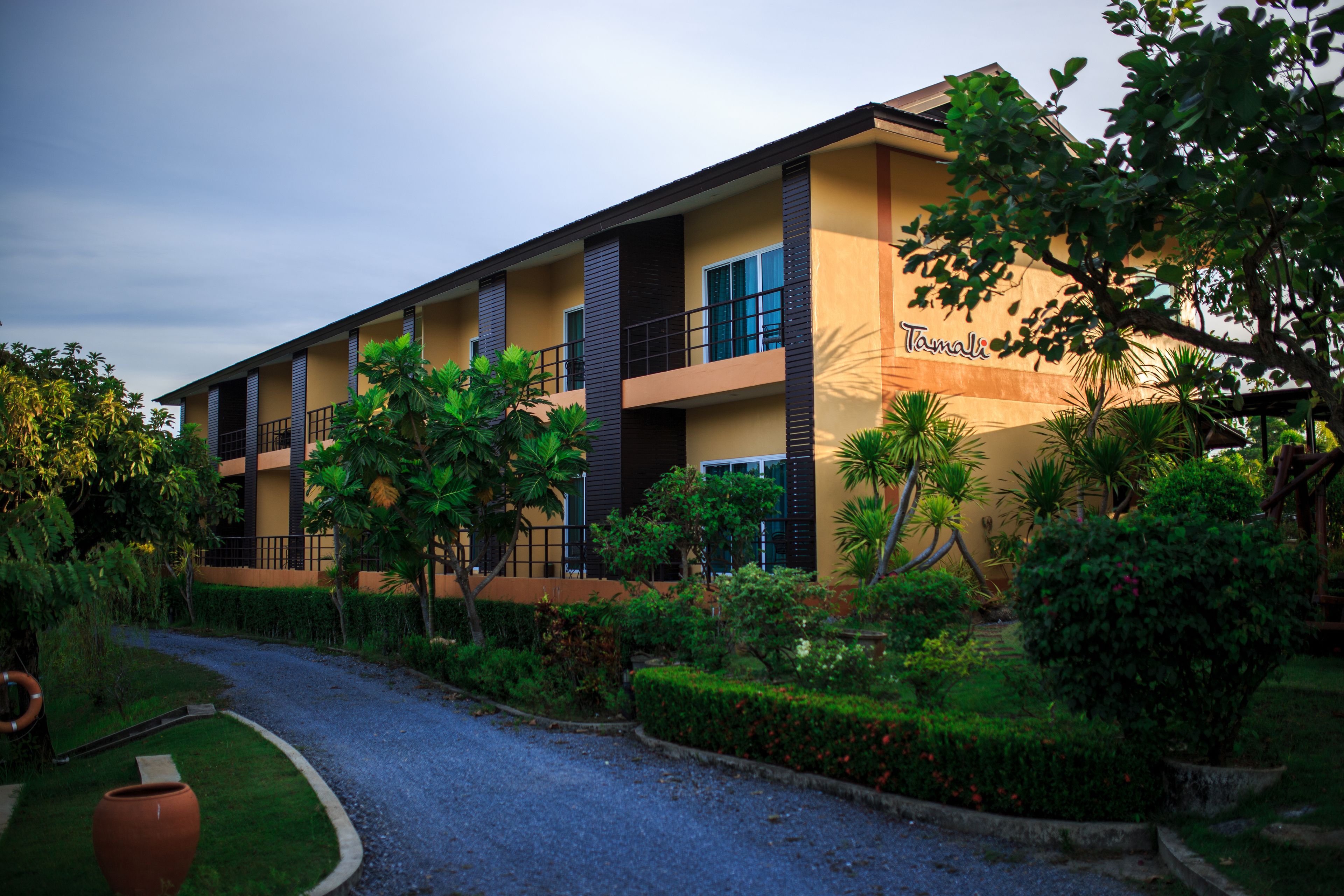 A multi-story hotel with a yellow facade, balconies, and lush greenery.