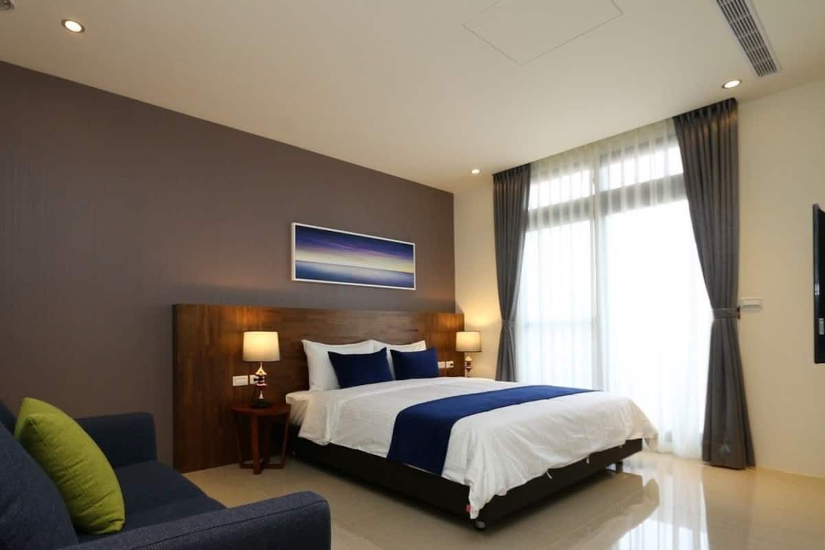 A hotel room with a large bed, a sofa, a small table, and a painting on the wall.