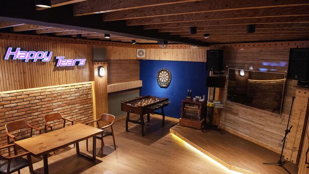 A cozy room with a foosball table, a dartboard, and a bar area. - Twelve Motel (Chilgok)