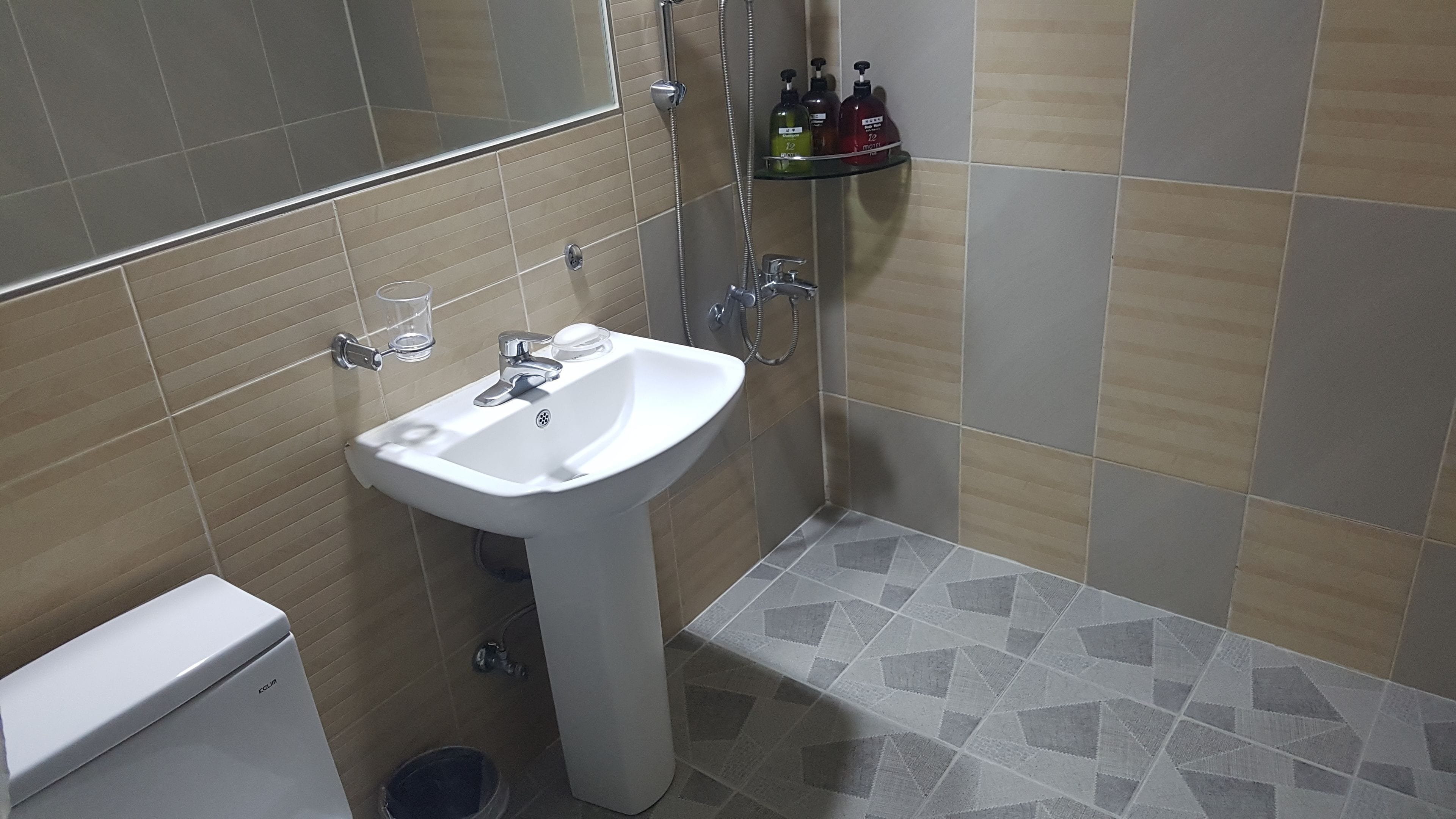 A bathroom with a white sink, a glass of water, and toiletries on a shelf.