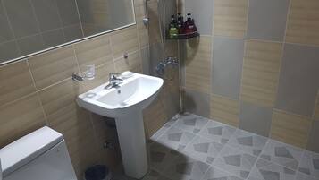 A bathroom with a white sink, a glass of water, and toiletries on a shelf.