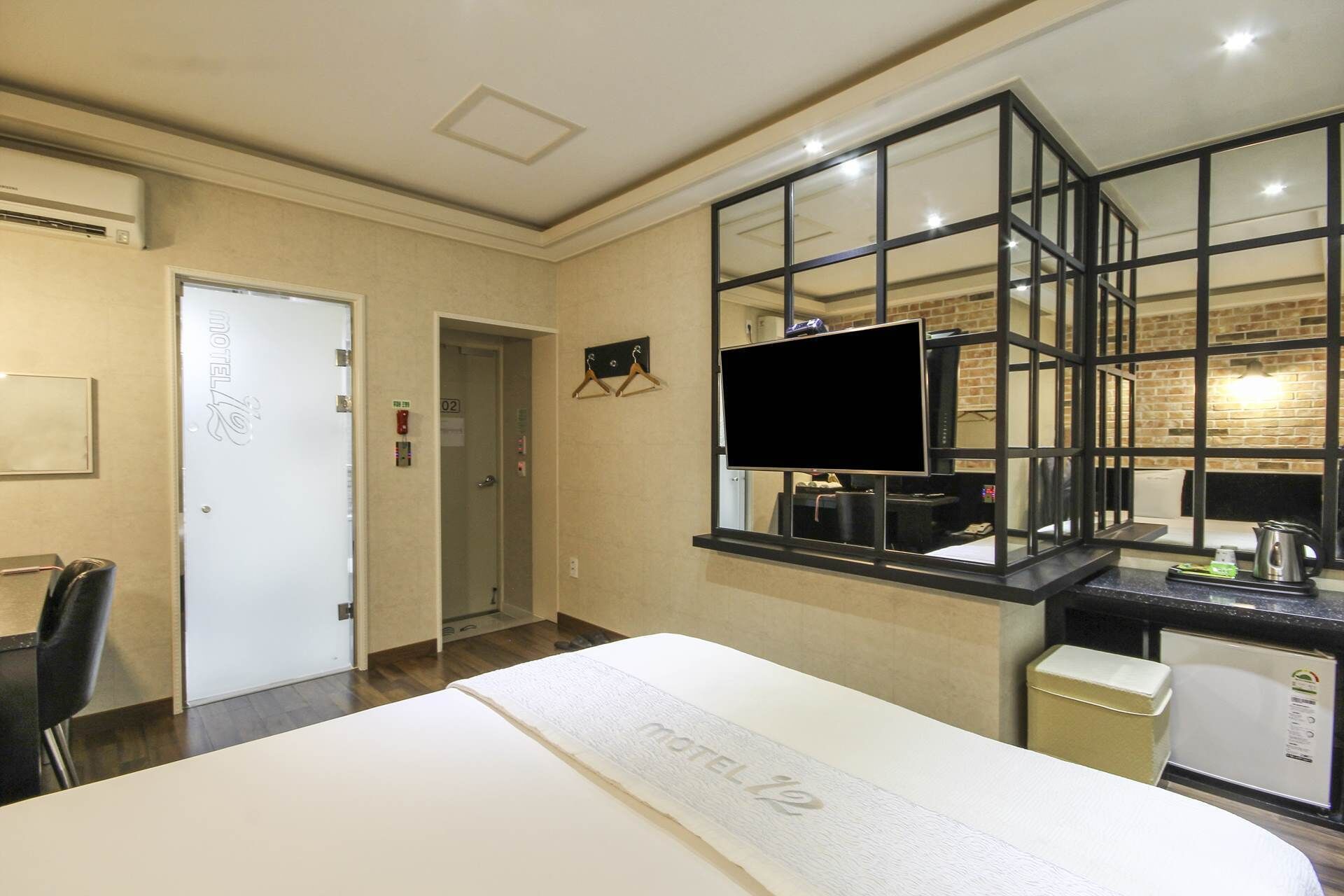Une chambre d’hôtel avec un lit, un bureau équipé d’un ordinateur, une télévision et une fenêtre donnant sur la ville.