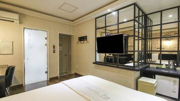 Une chambre d’hôtel avec un lit, un bureau équipé d’un ordinateur, une télévision et une fenêtre donnant sur la ville.