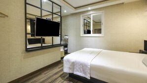 A hotel room with a bed, a TV mounted on the wall, a window, and a mirror. - Twelve Motel (Chilgok)