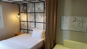 Ein Schlafzimmer mit einem Bett, einem Nachttisch, einer Wandregal und einem Beistelltisch.