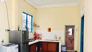 A compact kitchen with a refrigerator, stove, and washing machine. - Memory Vintage Home Da Lat (Cam Ly - Da Lat)