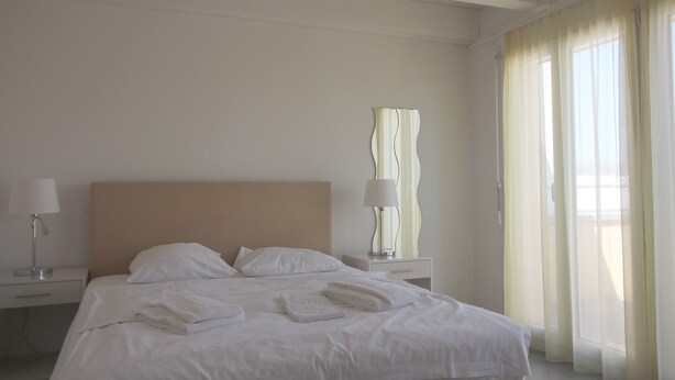 A hotel room with a bed, two bedside tables, a lamp, and a window with curtains. - Swiss Star District 11 (Zürich)