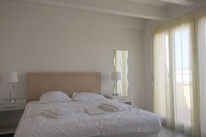 Una habitación de hotel con una cama, dos mesitas de noche, una lámpara y una ventana con cortinas.