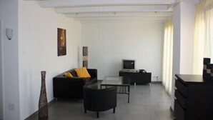 A modern living room with a sofa, a coffee table, a TV, and a desk. - Swiss Star District 11 (Zürich)