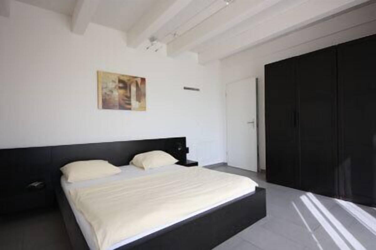 Ein Schlafzimmer mit einem großen Bett, einem dunklen Kleiderschrank und einem Gemälde an der Wand.