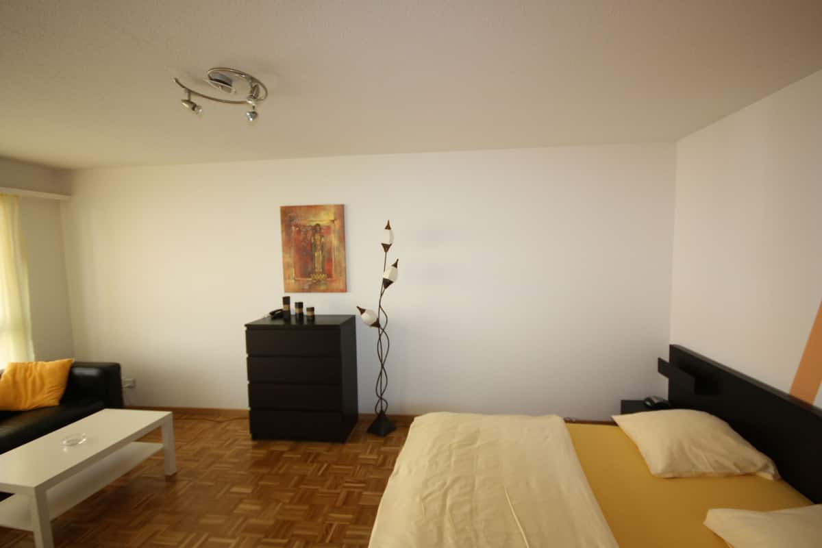 Ein Schlafzimmer mit einem Bett, einem Schminktisch, einem Nachttisch, einem Schreibtisch und einem Bild an der Wand.