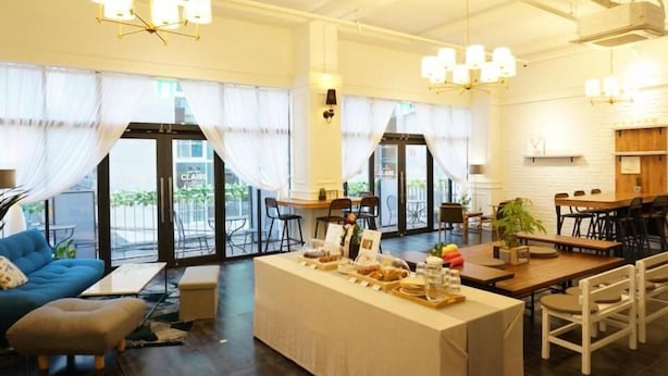 Un amplio vestíbulo de hotel con mostrador de recepción, zona de estar y grandes ventanales.