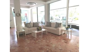 A spacious room with a large window, a white sofa, a small table, and a chair. - Hotel Ambasciata (Riccione)