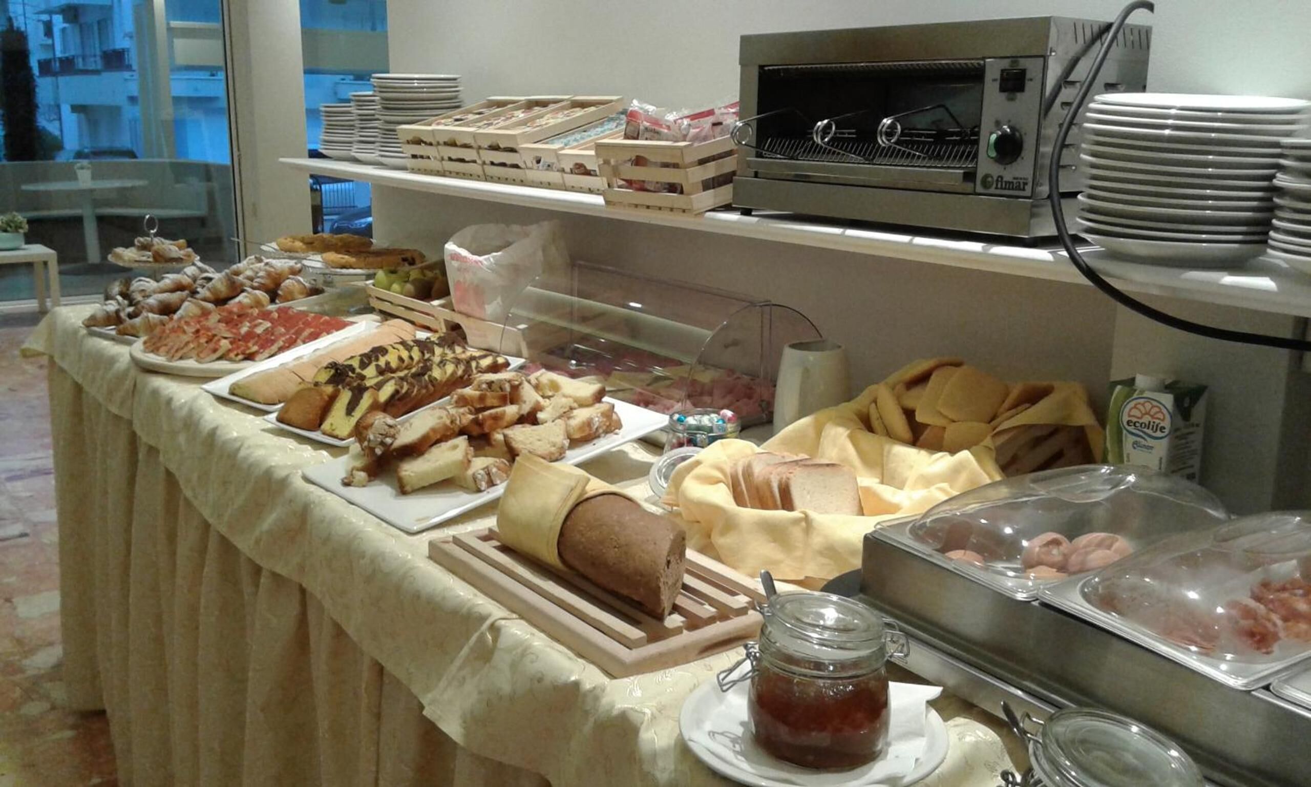 A buffet with various food items, including pastries, bread, and a meat spread.