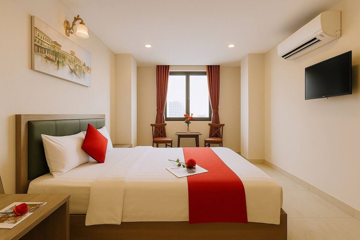 A hotel room with a bed, a TV, an air conditioner, a window with curtains, and a painting on the wall.