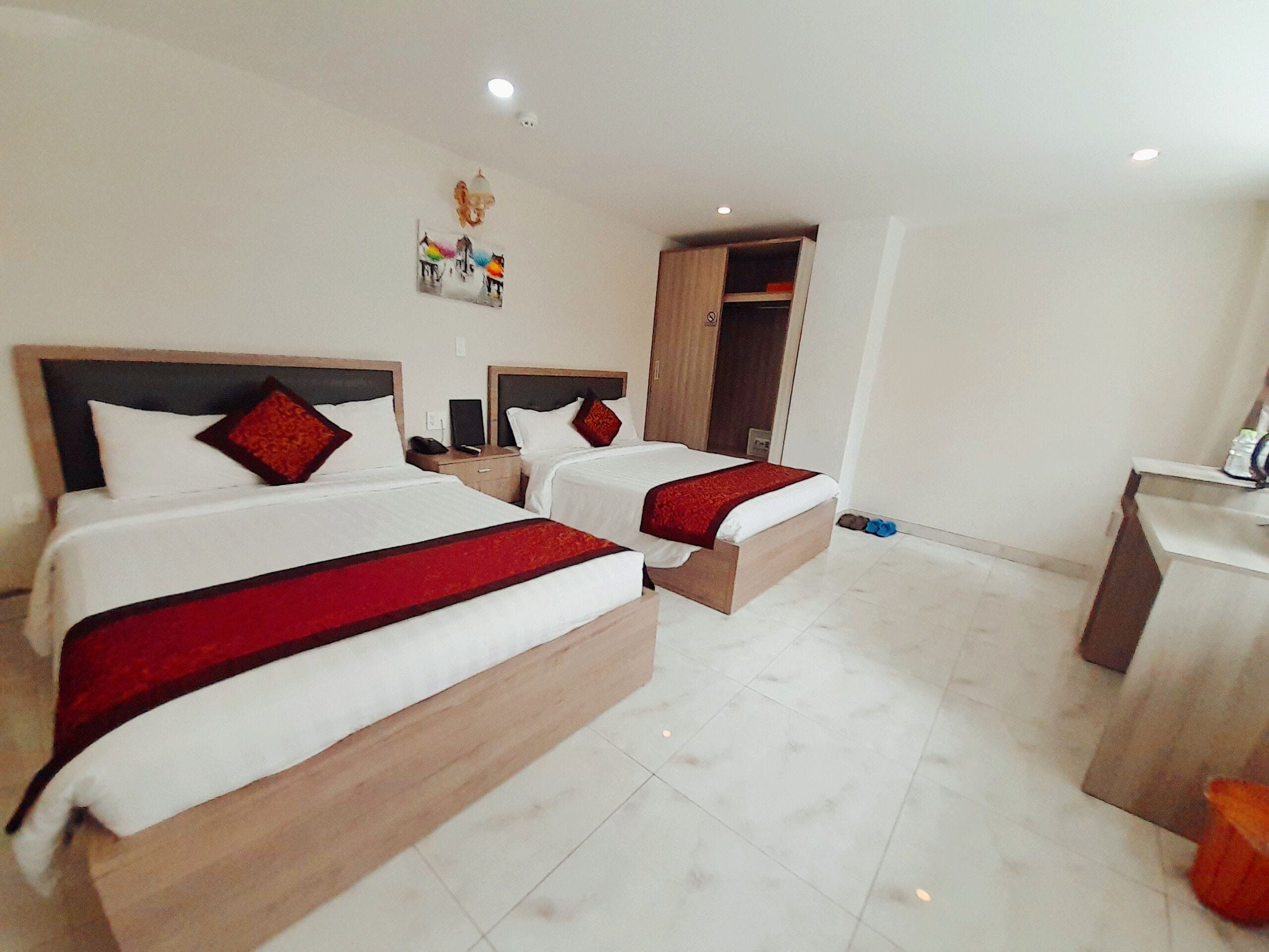 A hotel room with two beds, a desk, and a wardrobe.