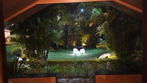 A view of a lush garden with a seating area and a small structure, likely a gazebo, surrounded by dense foliage. - Hill 'N' You - A Boutique Garden Resort (Abu Road)