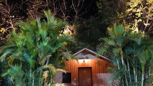 A wooden cabin surrounded by lush greenery at night. - Hill 'N' You - A Boutique Garden Resort (Abu Road)