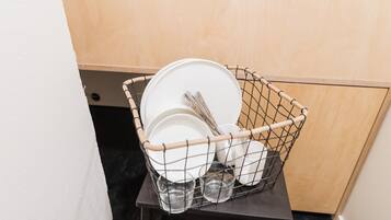 A wire basket containing plates, bowls, and glasses on a small table.