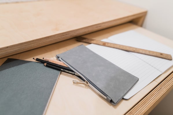 Un escritorio de madera con un cuaderno, lápices y una regla.