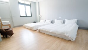 A hotel room with two beds, a wooden floor, a chair, and a small brown animal-shaped ottoman. - M House (Hualien City)
