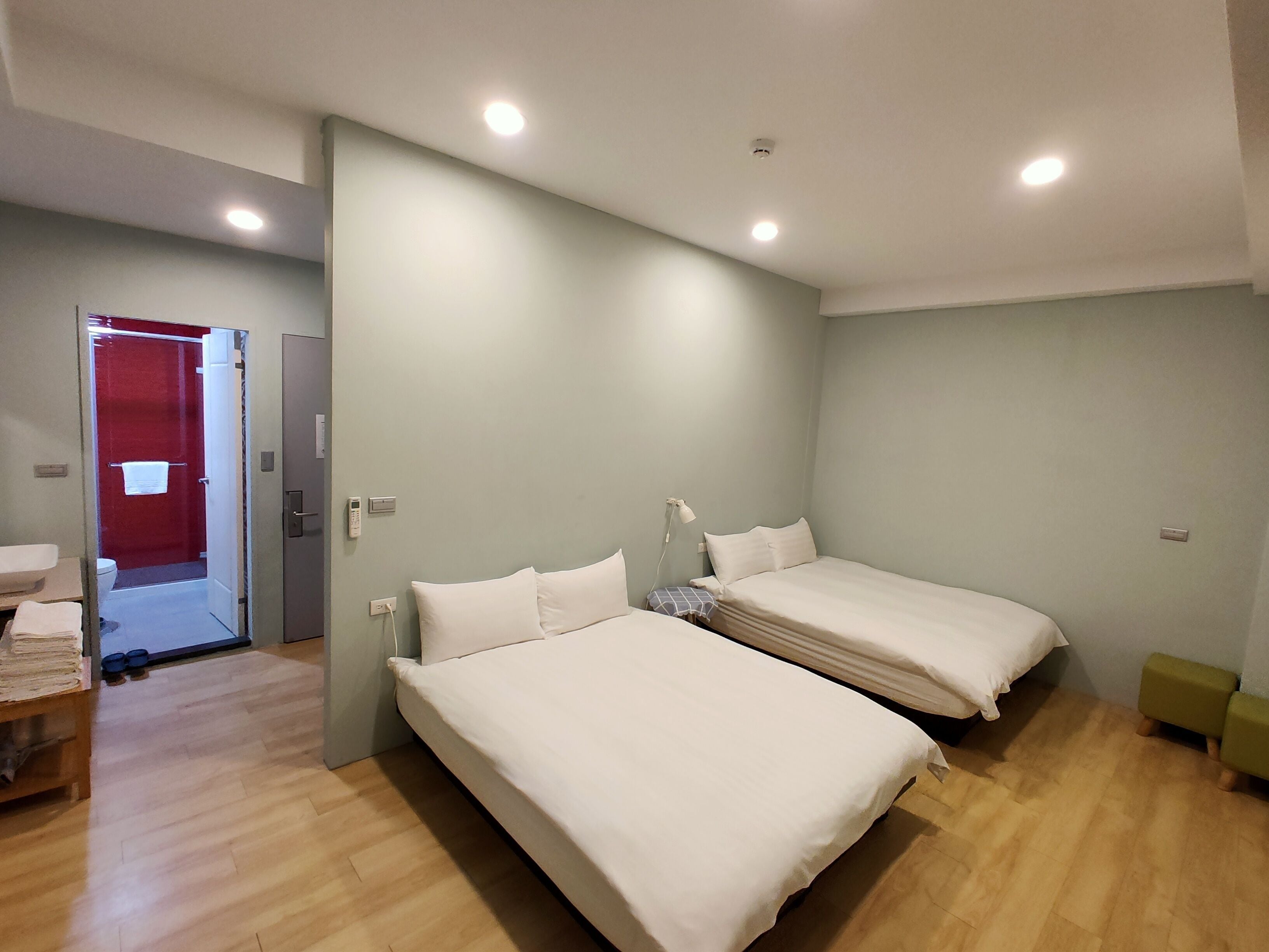 A modern bedroom with two beds, a shower, and a wooden floor.