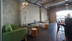 A modern interior with a green sofa, stools, a bar area, and a stone wall. - M House (Hualien City)