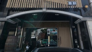 A building with a prominent 'MI' sign above the entrance, a wooden slatted awning, and a large glass window. - M House (Hualien City)