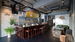 A bar area with a long counter, multiple stools, and a variety of bottles. - M House (Hualien City)