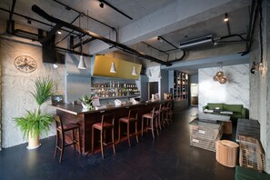 A bar area with a long counter, multiple stools, and a variety of bottles. - M House (Hualien City)